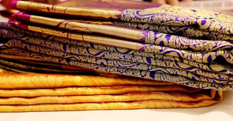 A stack of luxurious Kanchipuram silk sarees showcasing intricate patterns and vibrant colors.